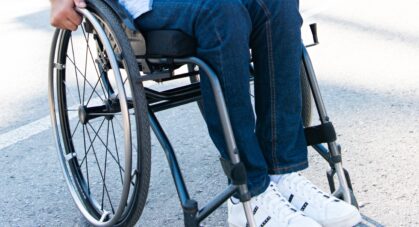 handsome smiling man using wheelchair on street and looking up