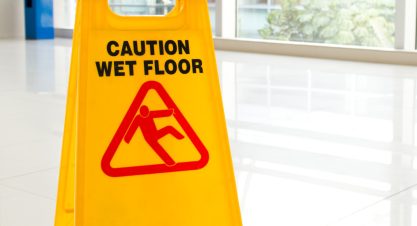Woman slips next to wet floor sign