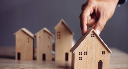 Businessman,Choosing,Mini,Wood,House,Model,From,Model,On,Wood
